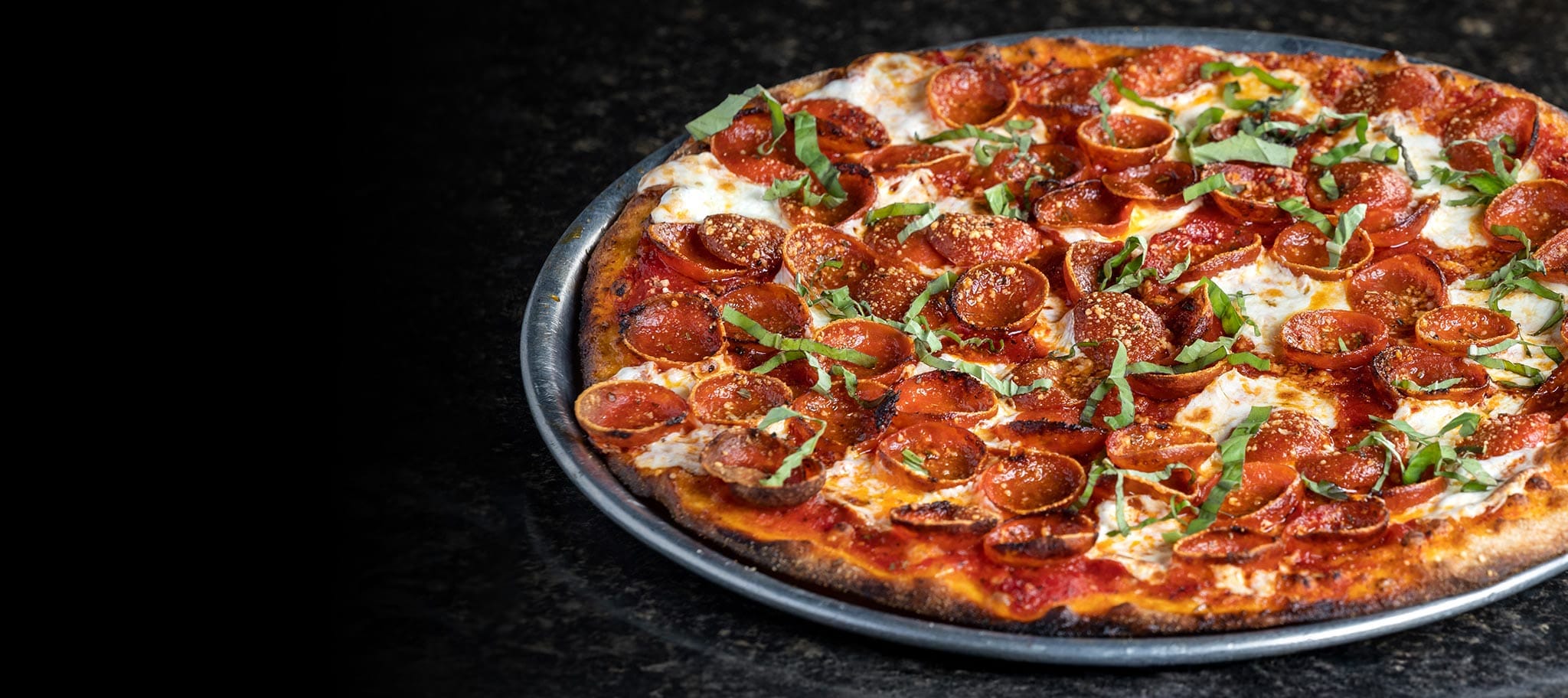 A pizza with pepperoni, sitting on a serving pan