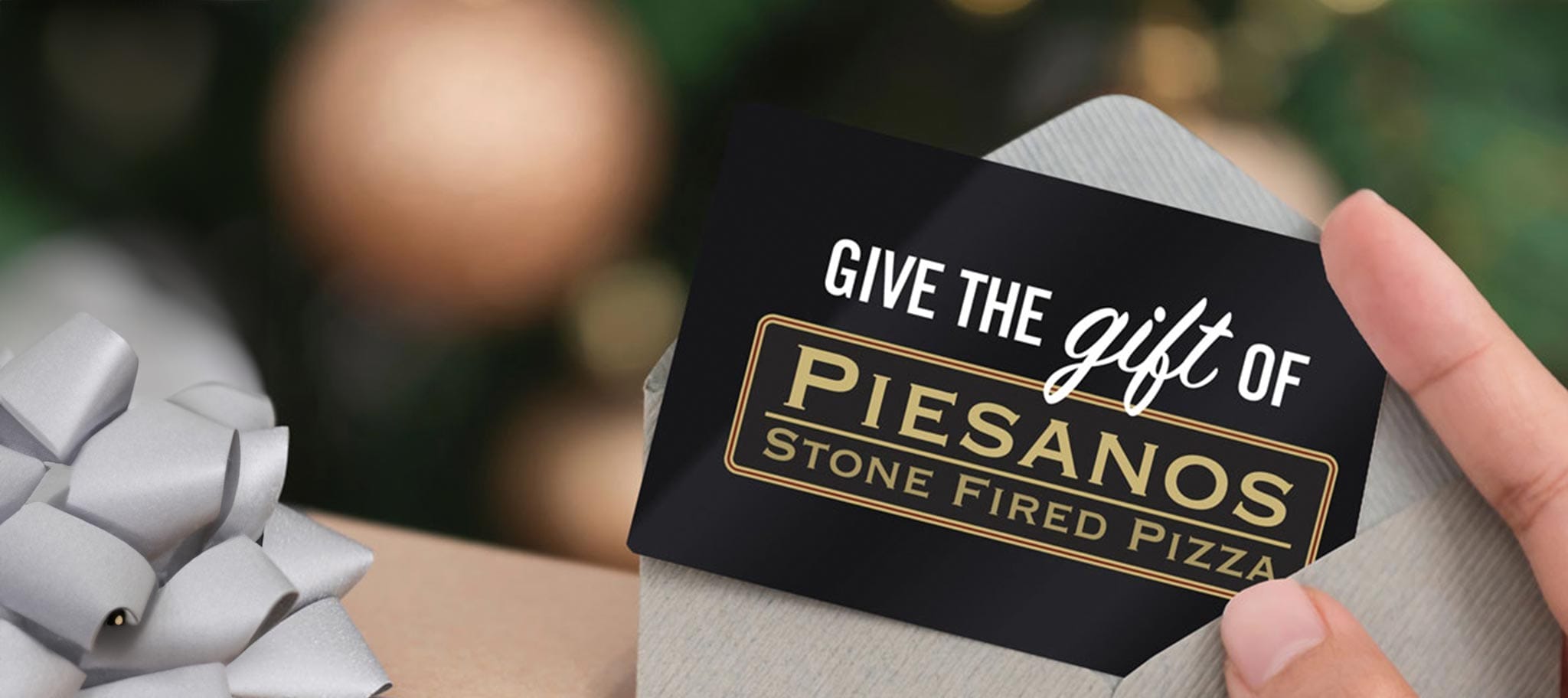 Hand holding an envelope containing a Piesanos gift card